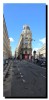 Rue avec du marquage au sol, à gauche la façade d'un immeuble, en face un immeuble mince arrondi.